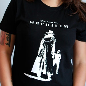 May include: Black t-shirt with a white graphic of a figure in a long coat and hat. The text "Fields of the Nephilim" is printed above the graphic.