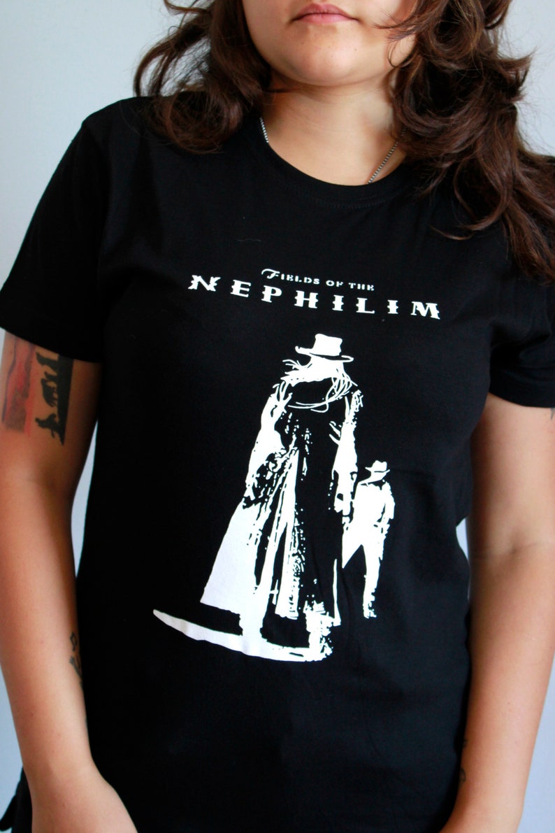 May include: Black t-shirt with a white graphic of a figure in a long coat and hat. The text "Fields of the Nephilim" is printed above the graphic.