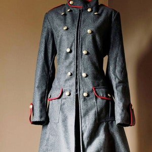May include: A gray wool coat with a red trim and gold buttons. The coat has a zipper closure and a stand-up collar.