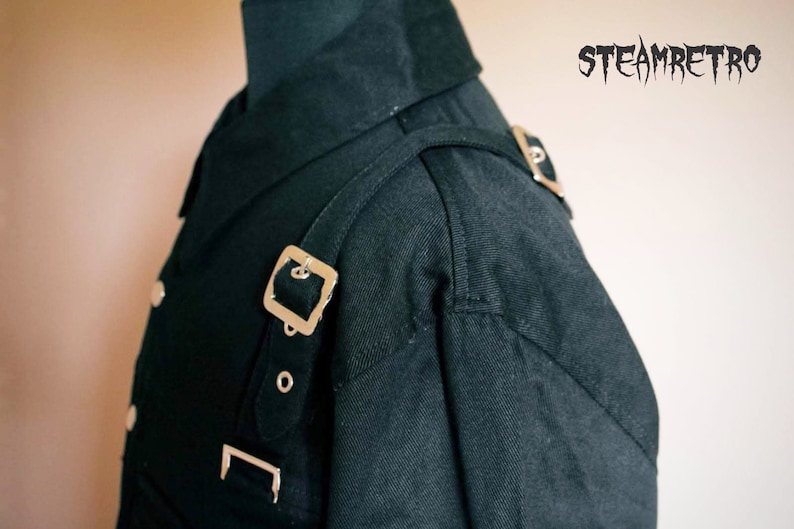May include: A black collared shirt with a silver buckle strap across the shoulder. The shirt has a double breasted closure and a collar that stands up.