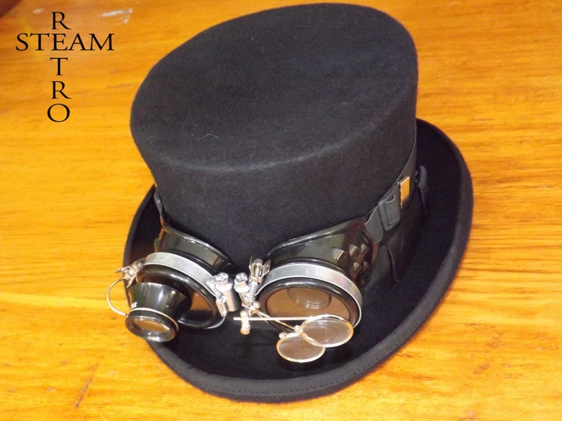 Peut inclure: Un chapeau haut de forme noir avec un bandeau noir et une paire de lunettes steampunk argent&eacute;es et noires fix&eacute;es &agrave; l'avant.