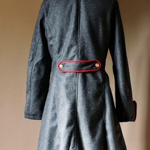 May include: A gray wool coat with a red trim and gold buttons. The coat has a long, flowing skirt and a high collar.