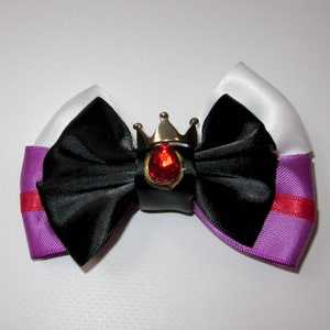 May include: A black satin bow with a purple and white ribbon, accented with a silver crown and a red gem.