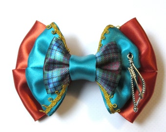 May include: A turquoise and orange bow with a plaid center and a silver arrow charm.