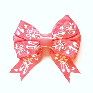May include: A pink bow with white ballet shoe and heart designs.
