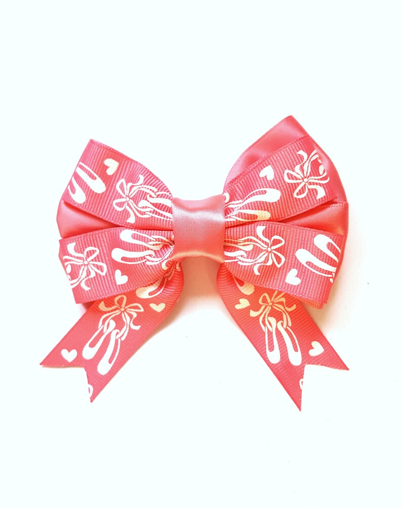 May include: A pink bow with white ballet shoe and heart designs.