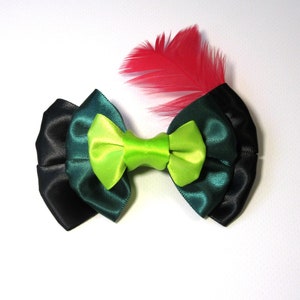 Puede incluir: Un lazo verde, negro y verde oscuro con un centro verde lima y un acento de pluma roja.
