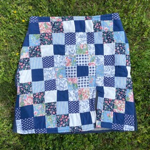 May include: A blue and white patchwork skirt with a floral pattern. The skirt is made of cotton and has a simple design.