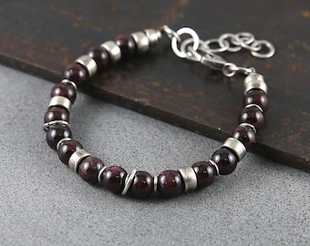 Puede incluir: Un brazalete de plata y granate con cierre de plata. El brazalete está hecho de pequeñas cuentas redondas que alternan plata y granate.