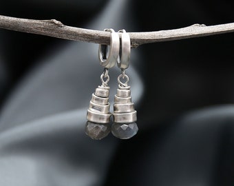 Peut inclure: Boucles d'oreilles créoles en argent avec un design en forme de cône superposé et une pierre précieuse gris foncé au bas.