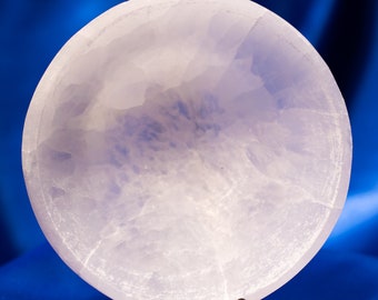 May include: A white selenite bowl with a smooth, polished surface. The bowl is on a black metal stand.