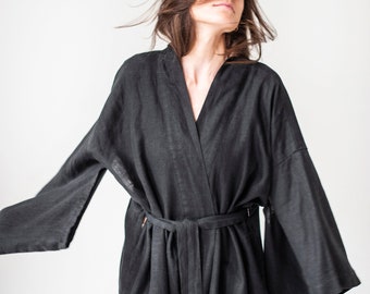 May include: A black linen robe with long sleeves and a tie belt. The robe is open in the front, revealing the neckline.