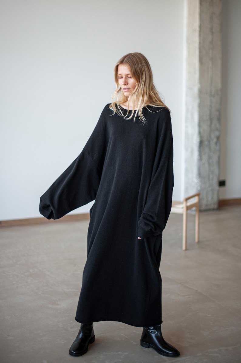 May include: A long black oversized sweater dress with long sleeves and a round neckline.