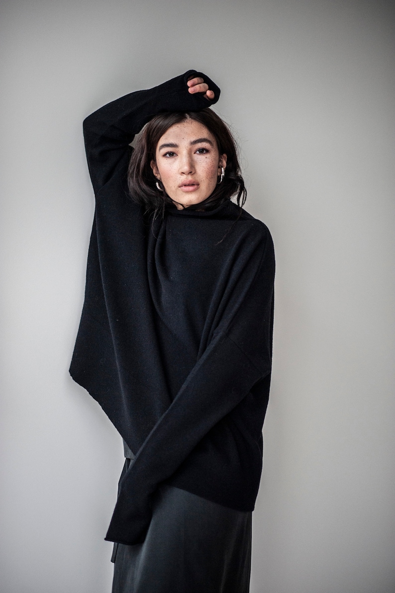 May include: A black turtleneck sweater with a loose fit and long sleeves. The sweater is made of a soft, comfortable material.