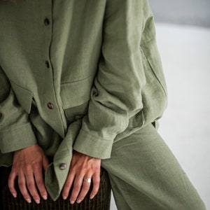 K&ouml;nnte beinhalten: Ein Ensemble aus Hemd und Hose aus Salbeigr&uuml;nem Leinen. Das Hemd hat einen Knopfleisten vorne und lange &Auml;rmel. Die Hose hat eine lockere Passform.