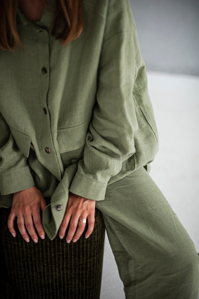 K&ouml;nnte beinhalten: Ein Ensemble aus Hemd und Hose aus Salbeigr&uuml;nem Leinen. Das Hemd hat einen Knopfleisten vorne und lange &Auml;rmel. Die Hose hat eine lockere Passform.