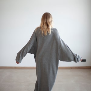 May include: A long, gray, oversized sweater with long sleeves. The sweater is made of a soft, comfortable material.
