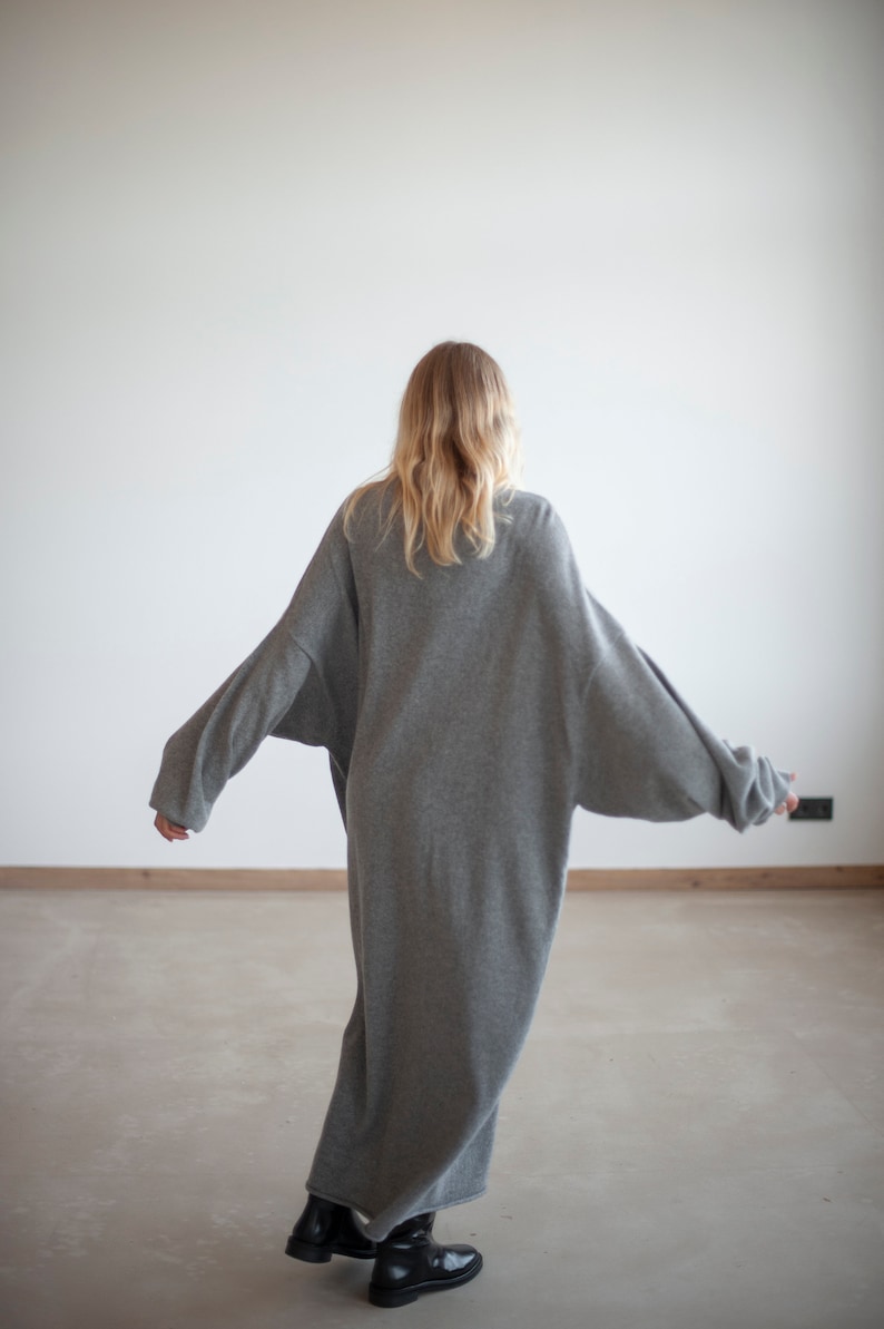 May include: A long, gray, oversized sweater with long sleeves. The sweater is made of a soft, comfortable material.