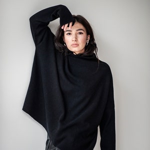 May include: A black mock neck sweater with long sleeves. The sweater is oversized and has a relaxed fit.