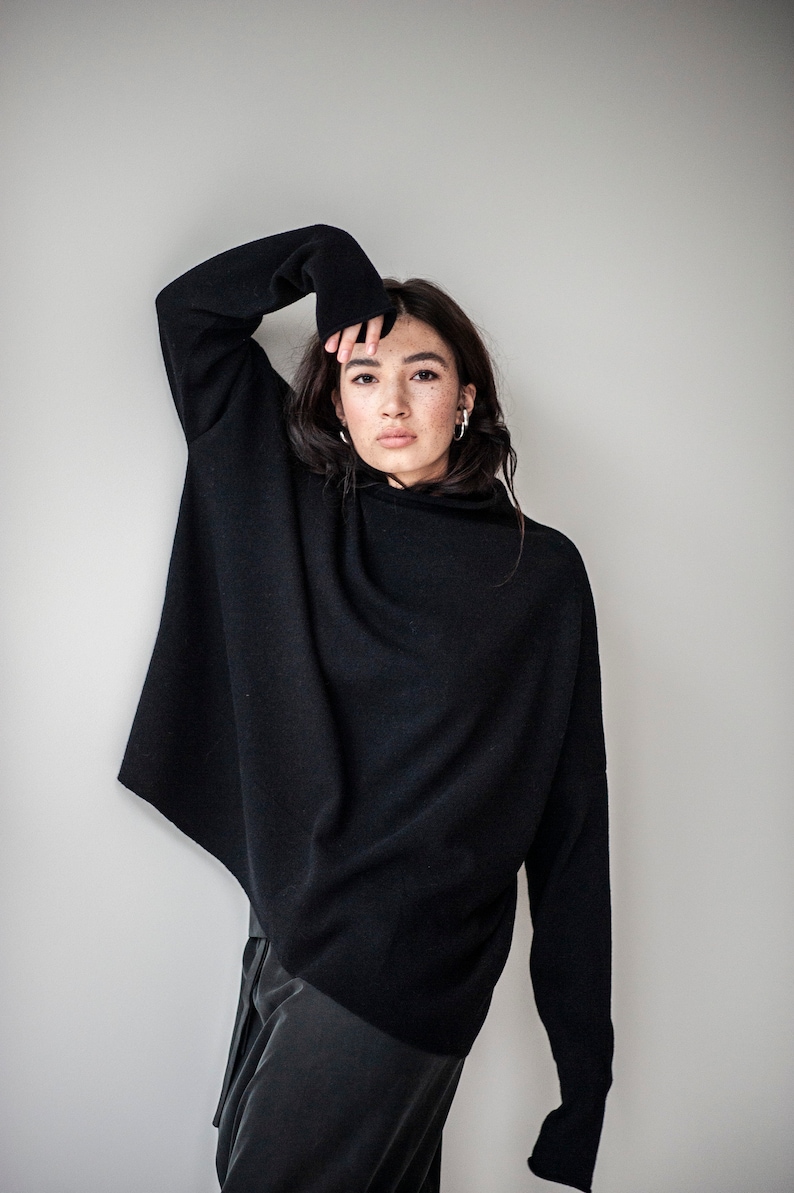 May include: A black mock neck sweater with long sleeves. The sweater is oversized and has a relaxed fit.