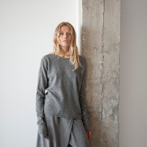 May include: A woman wearing a gray long-sleeved sweater and matching gray pants. The sweater has a relaxed fit and the pants are loose and flowy.