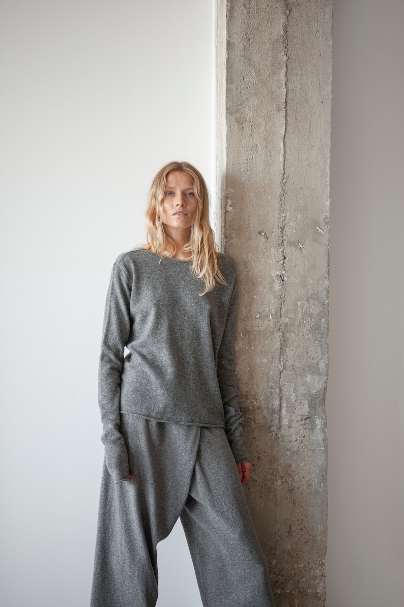 May include: A woman wearing a gray long-sleeved sweater and matching gray pants. The sweater has a relaxed fit and the pants are loose and flowy.