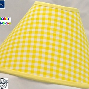 May include: Yellow and white gingham lampshade with a yellow trim. The lampshade is cone-shaped and has a white background with yellow squares.