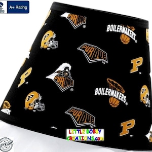May include: Black lampshade with a repeating pattern of Purdue University logos, including the Boilermakers basketball logo, the Purdue train logo, and the letter 'P'.