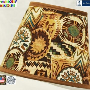 May include: A lampshade with a brown wooden trim and a patterned fabric featuring various basket designs in shades of brown, beige, and teal. The lampshade has a tapered shape and is labeled "LITTLE BOBBY CREATIONS".