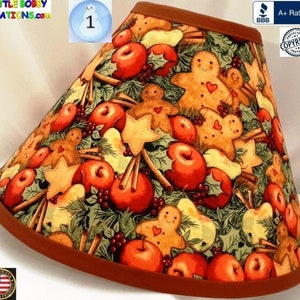 May include: A red, brown, and green lampshade with a gingerbread man, apple, and cinnamon stick pattern. The lampshade has a brown trim.