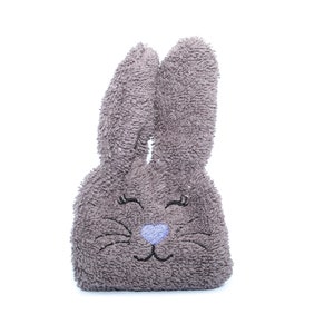 Puede incluir: Un conejito de peluche gris con ojos bordados y una nariz azul. El conejito est&aacute; hecho de un material suave y esponjoso.