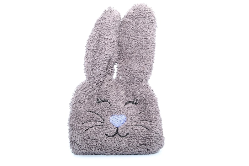 Puede incluir: Un conejito de peluche gris con ojos, nariz y bigotes bordados. El conejito est&aacute; hecho de un material suave y esponjoso.