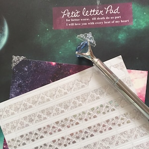 May include: A sheet of clear adhesive stickers with various designs, including stars, hearts, and circles. The stickers are arranged in rows on a white background. The text "Petit letter Pad" is visible at the top of the image.