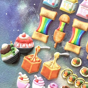 May include: A collection of colorful food-themed stickers, including rainbow toast, corn dogs, sushi, and ice cream. The stickers are arranged on a purple and blue background.