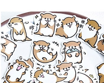 May include: A sheet of stickers featuring various cartoon otter illustrations. The otters are depicted in different poses and expressions, including holding fish, swimming, and waving. The stickers are printed on white paper with a glossy finish.