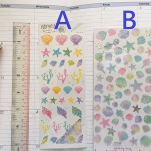 May include: Two sheets of stickers featuring a variety of sea-themed designs, including seashells, starfish, and coral. The stickers are on a white background and have a glossy finish. The text on the sticker sheet reads "YUR MASTE" and "Enjoy everyday life".