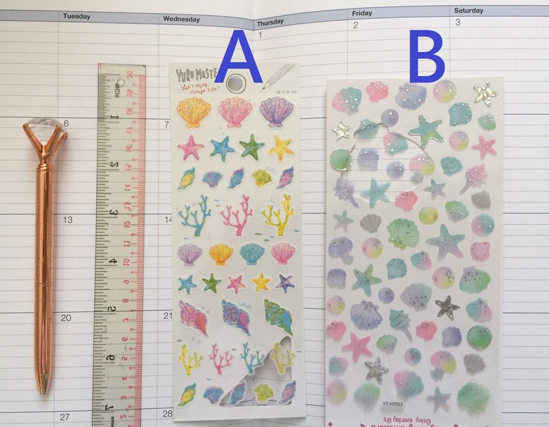 May include: Two sheets of stickers featuring a variety of sea-themed designs, including seashells, starfish, and coral. The stickers are on a white background and have a glossy finish. The text on the sticker sheet reads "YUR MASTE" and "Enjoy everyday life".