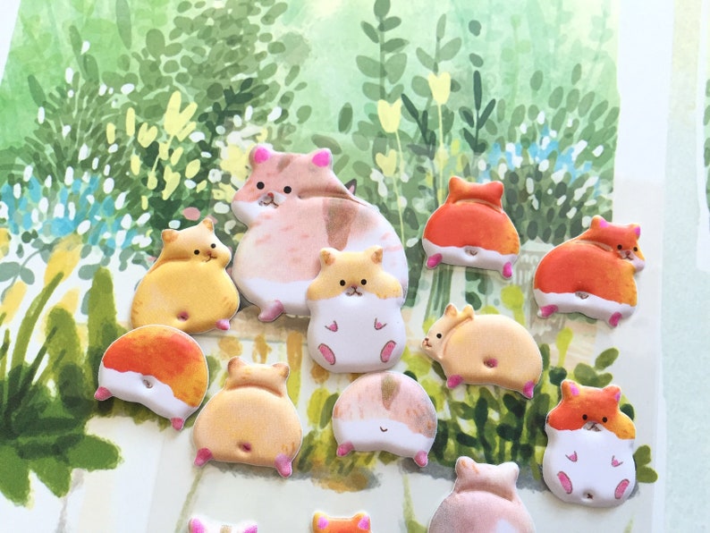 May include: A collection of 12 colorful hamster stickers with different poses. The stickers are made of a soft, puffy material and have a glossy finish. The hamsters are all wearing different expressions and have different colored fur.