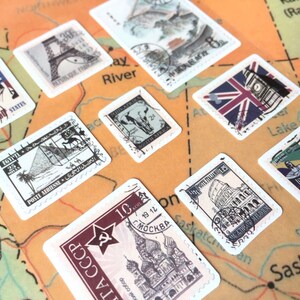 May include: A collection of vintage postage stamps featuring iconic landmarks from around the world, including the Eiffel Tower, Big Ben, the Statue of Liberty, and the Kremlin. The stamps are arranged on a map of North America.