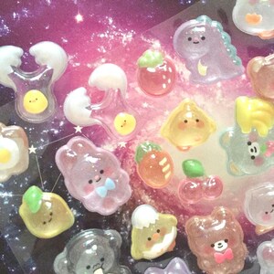 Pode incluir: Um conjunto de adesivos de resina translúcida coloridos com vários desenhos de animais e alimentos fofinhos. Os adesivos têm um efeito 3D e são perfeitos para adicionar um toque de fantasia a qualquer projeto.