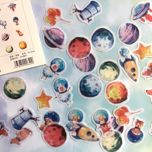 Puede incluir: Una hoja de pegatinas coloridas con ilustraciones de tem&aacute;tica espacial. Las pegatinas incluyen planetas, estrellas, cohetes, naves espaciales y astronautas. Las pegatinas son perfectas para a&ntilde;adir un toque de fantas&iacute;a a los diarios, planificadores y otros proyectos creativos.