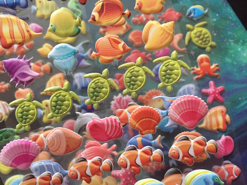 Puede incluir: Una hoja de pegatinas de pl&aacute;stico en 3D de colores que representan varias criaturas marinas, incluyendo peces, tortugas, conchas marinas y un pulpo. Las pegatinas son perfectas para a&ntilde;adir un toque de fantas&iacute;a a las manualidades, los diarios y otros proyectos.