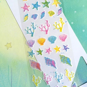 May include: A sheet of colorful stickers featuring various sea-themed illustrations, including seashells, starfish, and coral. The stickers are on a white background with the text "Yuru Paste Let's enjoy collage life!" at the top.