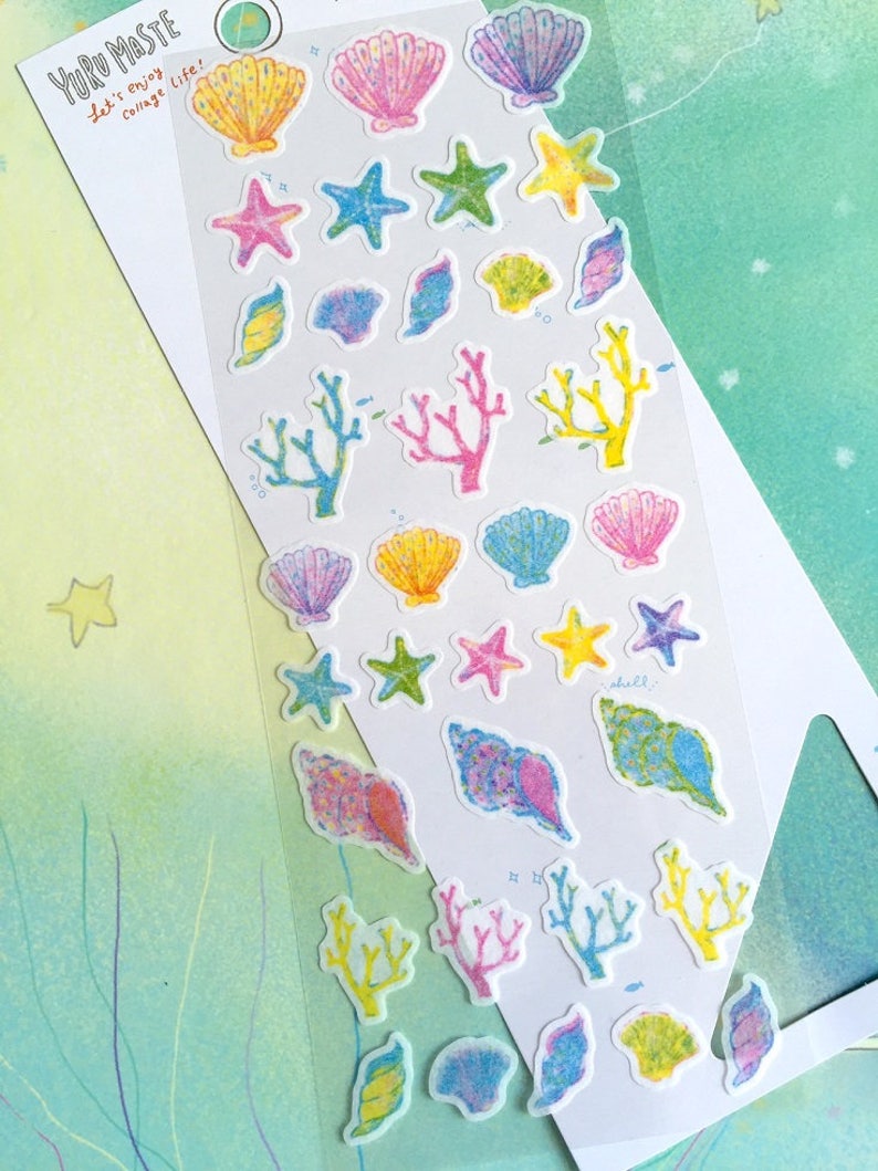 May include: A sheet of colorful stickers featuring various sea-themed illustrations, including seashells, starfish, and coral. The stickers are on a white background with the text "Yuru Paste Let's enjoy collage life!" at the top.