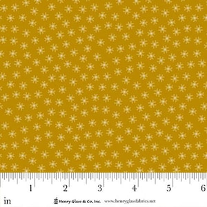 Könnte beinhalten: Senfgelber Stoff mit einem sich wiederholenden Muster aus kleinen, weißen, sternförmigen floralen Designs. Der Stoff wird mit einem Lineal in Zoll gemessen, was einer Breite von etwa 15 cm entspricht. Der Stoff ist von Henry Glass & Co.