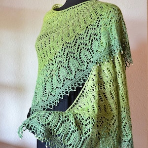 May include: A green and white crocheted shawl with a delicate lace pattern and beaded edges.