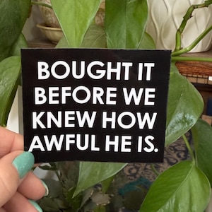 May include: Black and white sticker with the text "Bought it before we knew how awful he is."