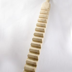 May include: A wooden dowel with a series of steps carved into it. The dowel is light brown and has a smooth finish.