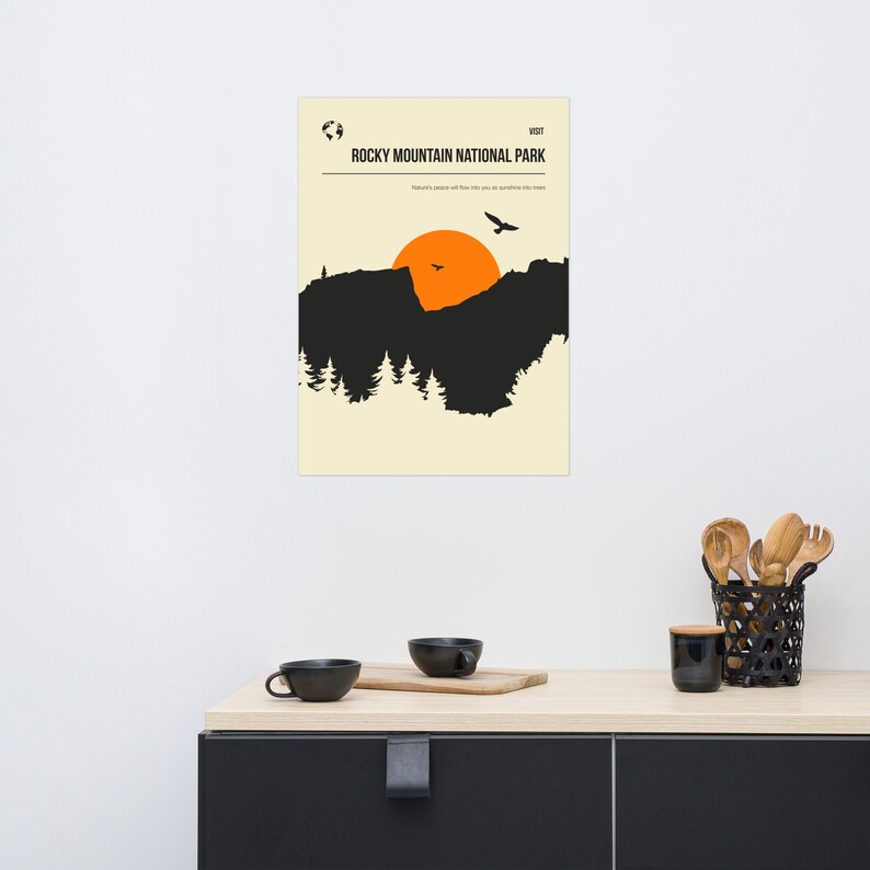 Op de afbeelding: Een minimalistische poster met een zwart silhouet van een bergketen en een ondergaande zon. De tekst "Rocky Mountain National Park" staat bovenaan de poster, met daaronder de woorden "Nature's peace will flow into you as sunshine flows into trees".