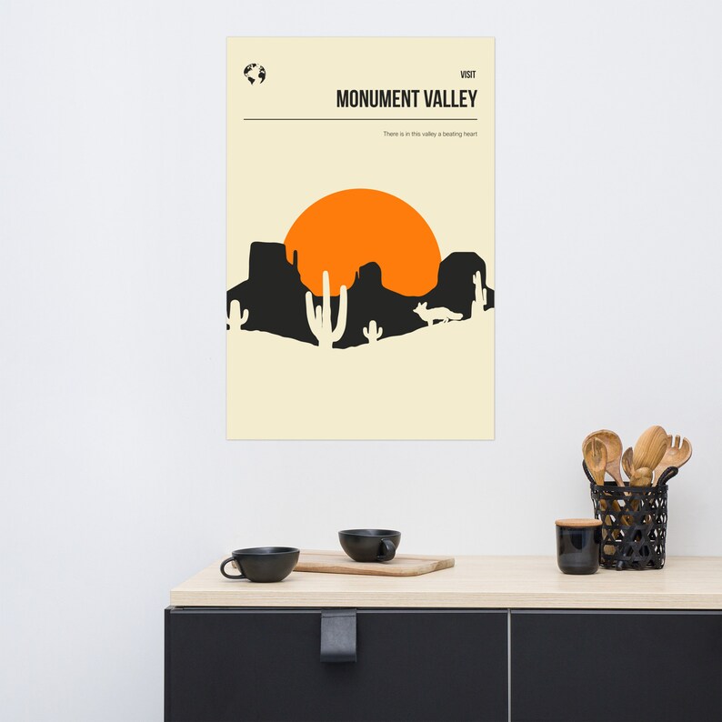 Peut inclure: Une affiche minimaliste avec une silhouette noire de Monument Valley, en Arizona, avec un grand soleil orange en arri&egrave;re-plan. Le texte "VISIT MONUMENT VALLEY" est en haut de l'affiche, et le texte "There is in this valley a brooding heart" est en bas.
